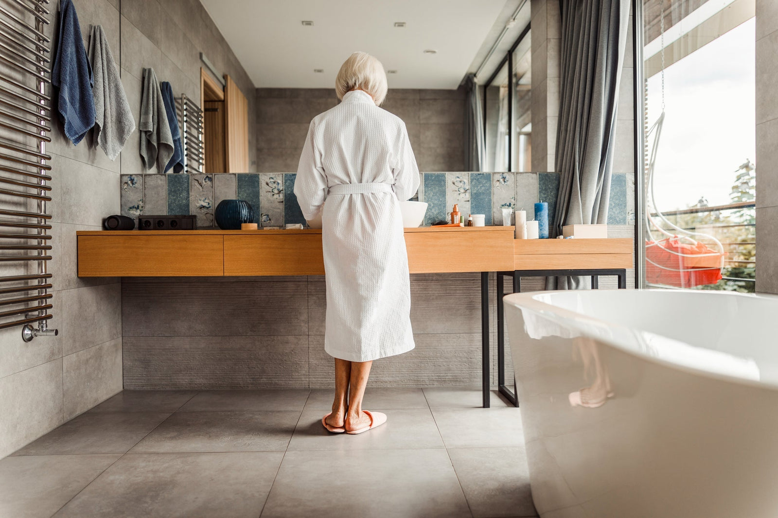 Woman standing in a bathroom looking in the mirror at her vanity