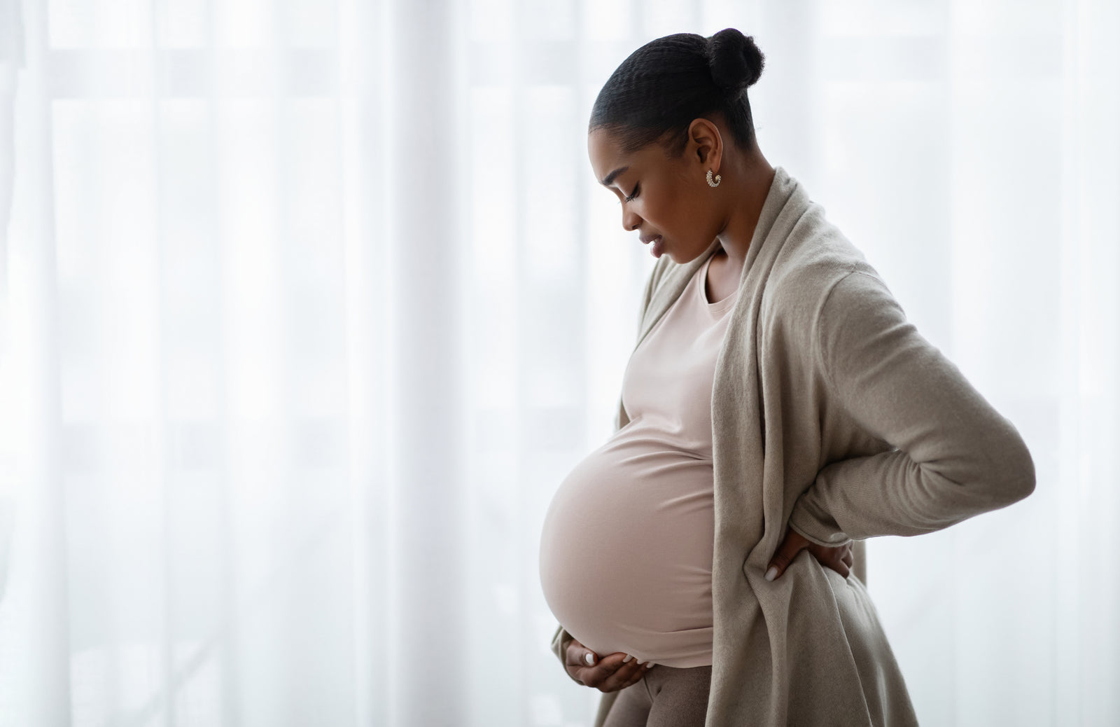 A pregnant woman looks at her stomach.