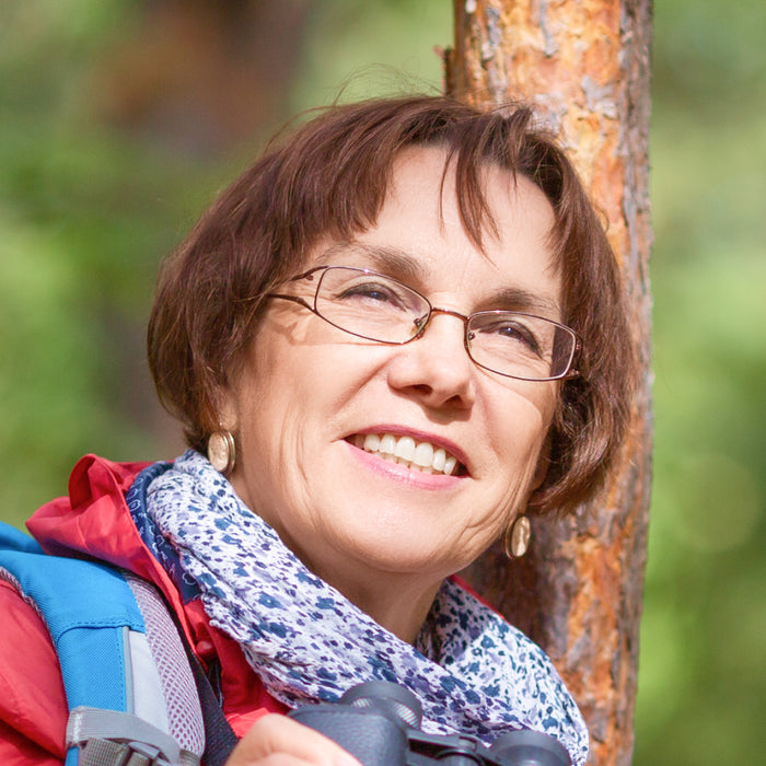 A woman smiling by a tree.