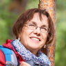 A woman smiling by a tree.