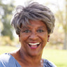 A woman smiling in a park.