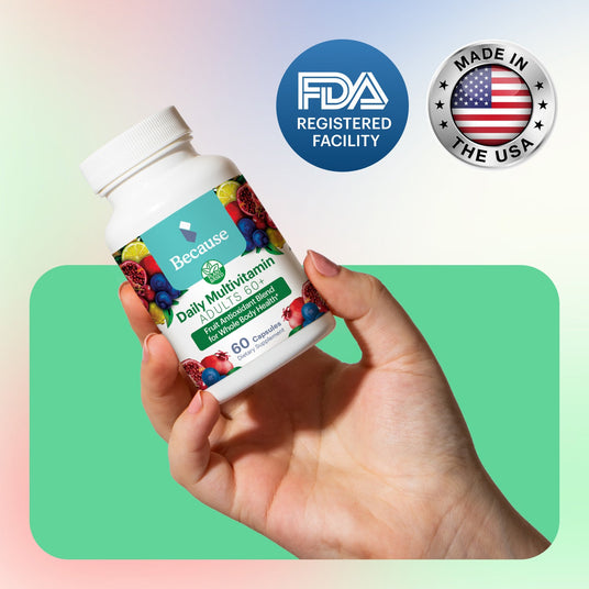 A hand holding Because Market Daily Multivitamin with two seals reading "FDA Registered Facility" and "Made in the USA"