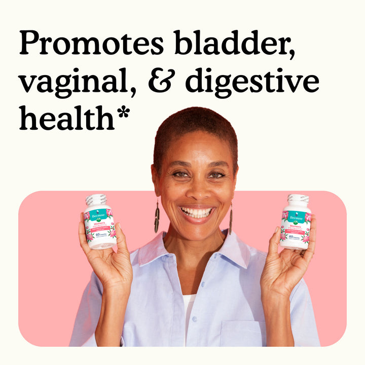Smiling woman holding two bottles of Because Women's Probiotic with text "promote vaginal & digestive health" on white and pink background