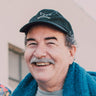 A man in a hat smiles.