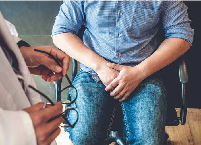 A man sits in a doctors office listening to a doctor.