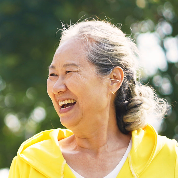 A woman exercises outside and smiles.