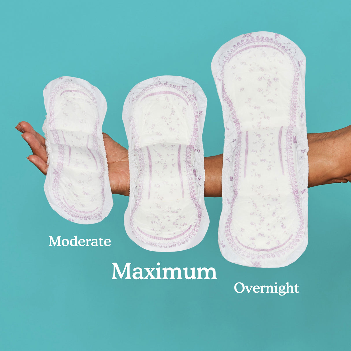 Arm/ hand holding three pads. Moderate, Maximum, and Overnight.