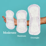 A woman holding moderate, maximum, and overnight pads in her arm with moderate being the shortest and smallest pad