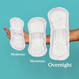 A woman holding a moderate, maximum, and overnight pad in her arm with the overnight pad being the largest