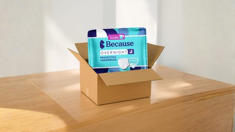 Package of Because Overnight Underwear displayed in a brown, unmarked delivery box, resting on a wooden surface