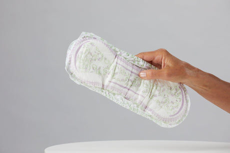 Hand holding Because incontinence pad on grey background
