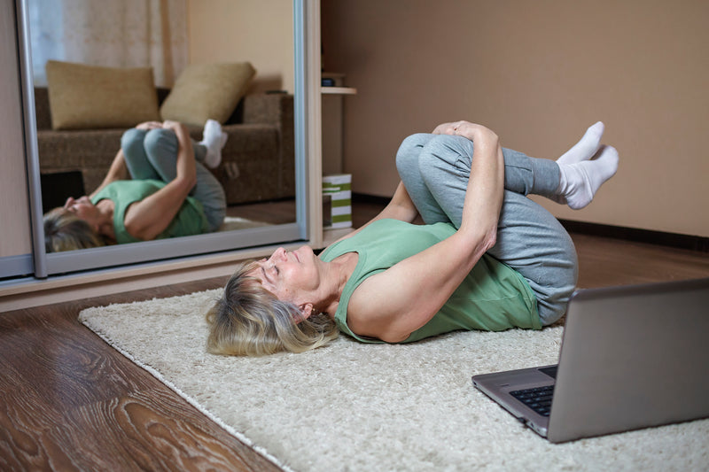 Woman laying on the floor hugging her knees to chest