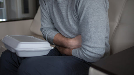 Man with his arms crossed leaning on a table