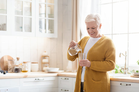 Woman in her kitchen pouring water into a glass