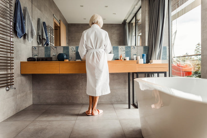 Woman standing in a bathroom looking in the mirror at her vanity