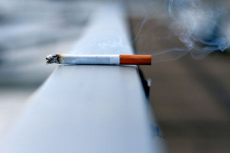 A cigarette balances on a ledge.