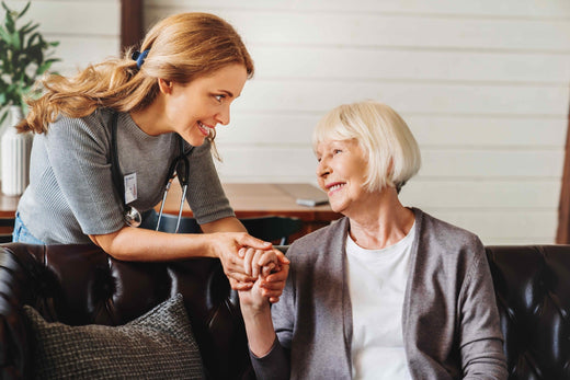 A younger woman holding the hand of an older woman with a blonde bob haircut