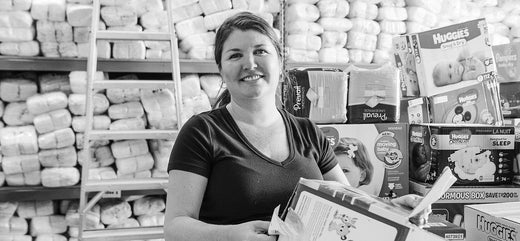 Woman smiling in front of a shelf full of diaper products