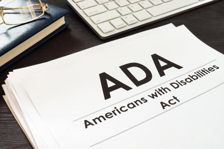 A stack of papers on a desk with "ADA - Americans with Disabilities Act" written on it