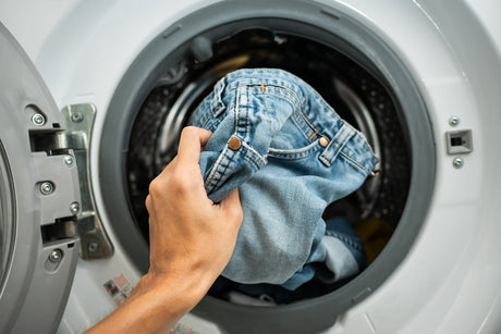 Person putting jeans in washer.