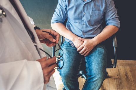 Man sitting in a doctors office with hands crossed over his lap