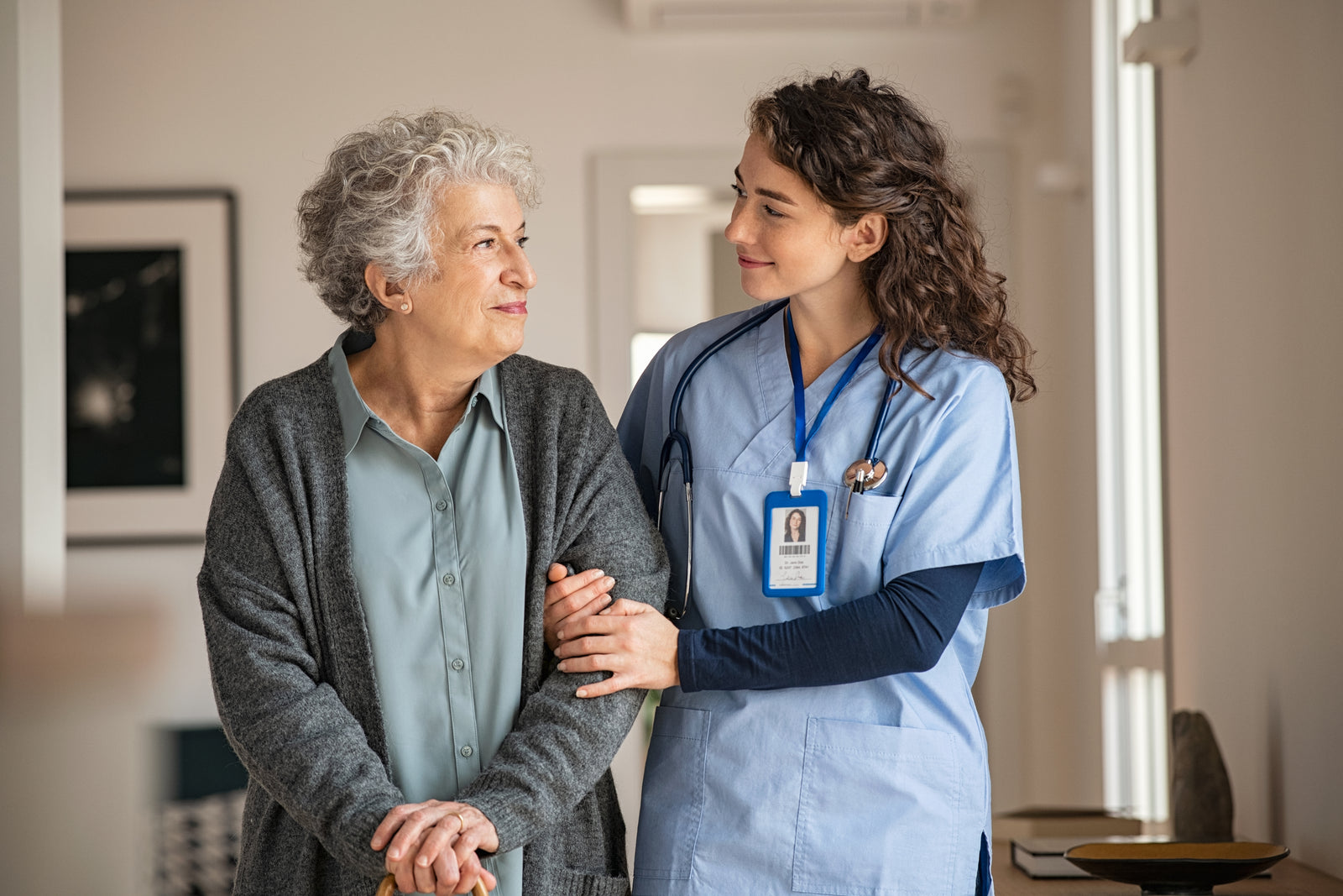 A medical professional walks with a patient down a hallway.