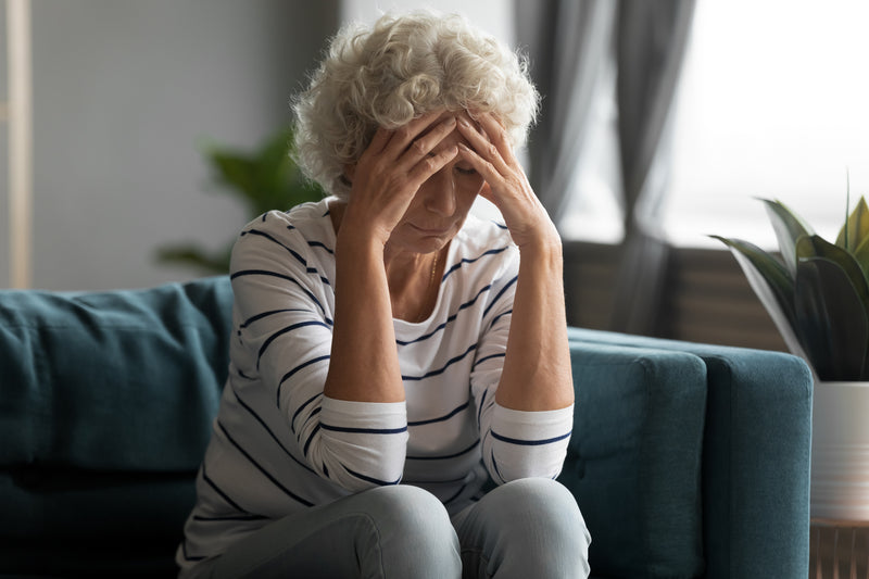 A stressed out woman holds her head in her hands.