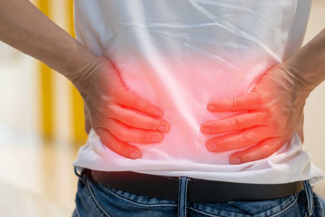 A person places their hands on their inflamed back in pain.