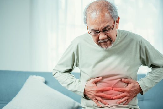 A man clutches his stomach in pain. There is a red overlay indicating inflammation in his abdomen.