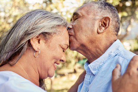 Senior couple, love and forehead kiss for care, passion and embrace for romantic relationship together in nature. 