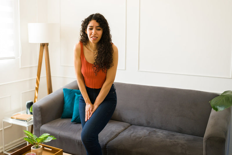 A woman holds her hands between her legs trying not to pee.