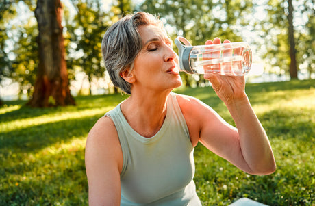 Woman drinking water outside.