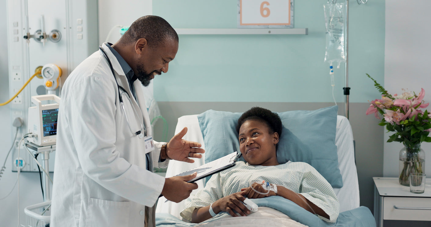 A woman in a hospital bed talking to a doctor.