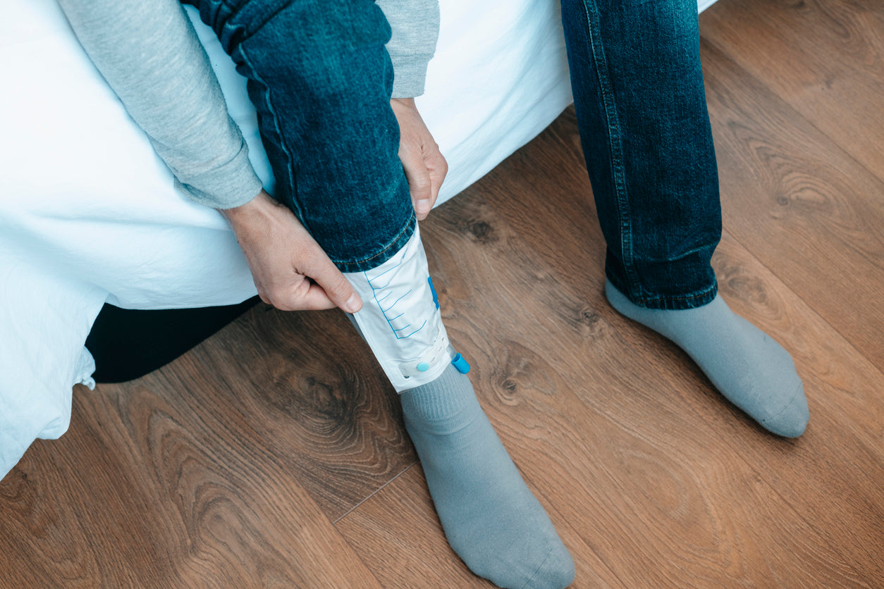 A person attaches a urine collection bag to their leg.