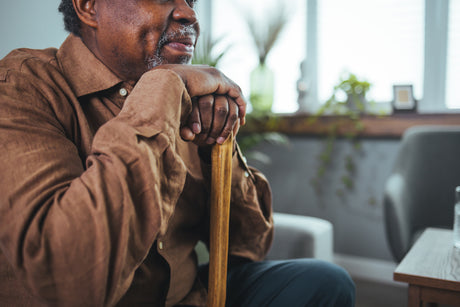 A man rests his chin on his cane.