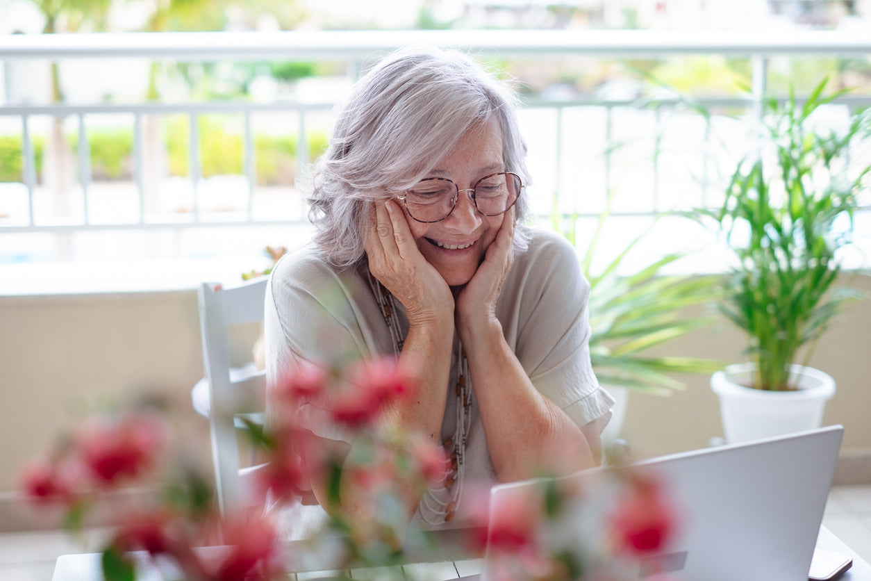 Happy smiling senior gray haired woman talking with a date by laptop webcam.