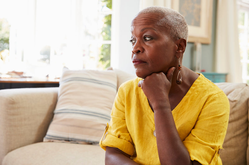A woman sits on a couch looking worried.