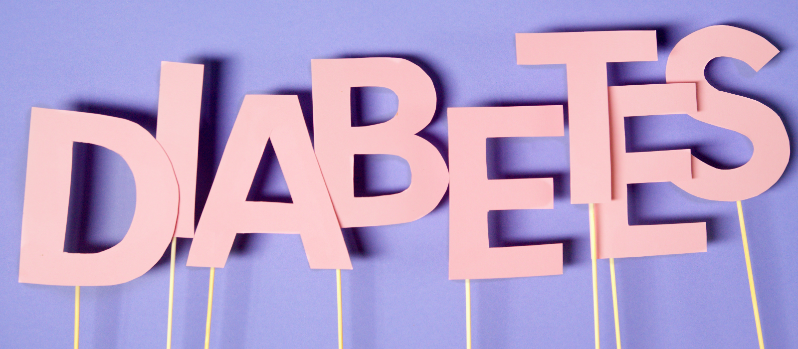 The word "diabetes" is spelled out on paper letters held on thin sticks.