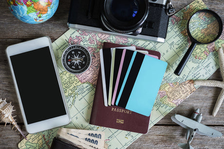 A printed map displaying Europe with a smartphone, pen, watch, DSLR camera and lens, and a pen laid on it.