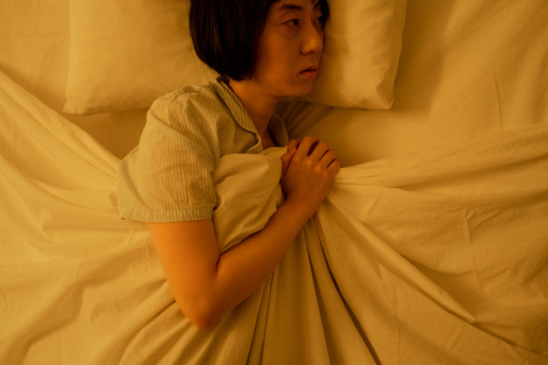 A woman lies in bed awake.
