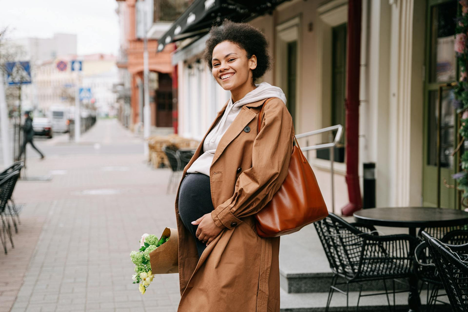 A pregnant woman smiles on the street.