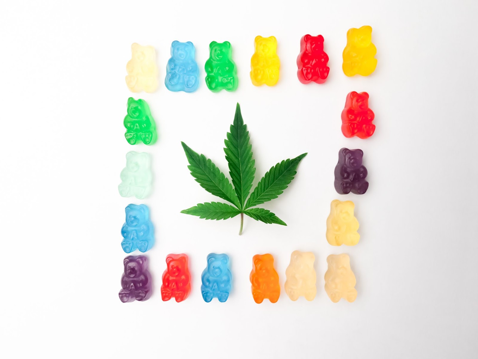 A green hemp leaf surrounded by colorful gummy bears