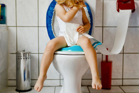 Young child sitting on a toilet as she learns to use the toilet