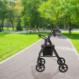 Side view of black foldable rollator walker. Walker contains a padded seat, room for storage under the seat, and handle brakes.