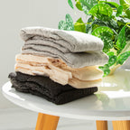 3 colors of Because Maximum Plus underwear stacked on white table beside a plant.