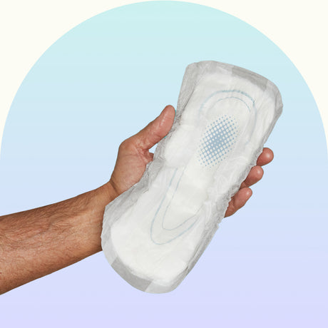 A hand holding an incontinence pad.