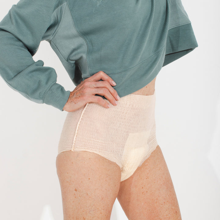 Person wearing a green long-sleeve top and beige Because underwear on a white background