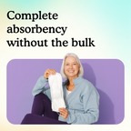 A smiling older woman with white hair sits against a purple wall holding up a slim Overnight pad, showing full absorbency without bulk.