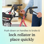 Pink Zebra Aluminum Folding Rollator Walker brake handles being held by a person, with text "push down on handles to brake and lock rollator in place quickly" on a light yellow background.