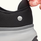 Two fingers holding heel tab on Black Women's Extra Wide Comfort Shoes on a white background